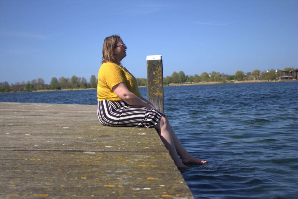 Vrouw die kijkt ove het water en worstelt met perfectionisme en angst